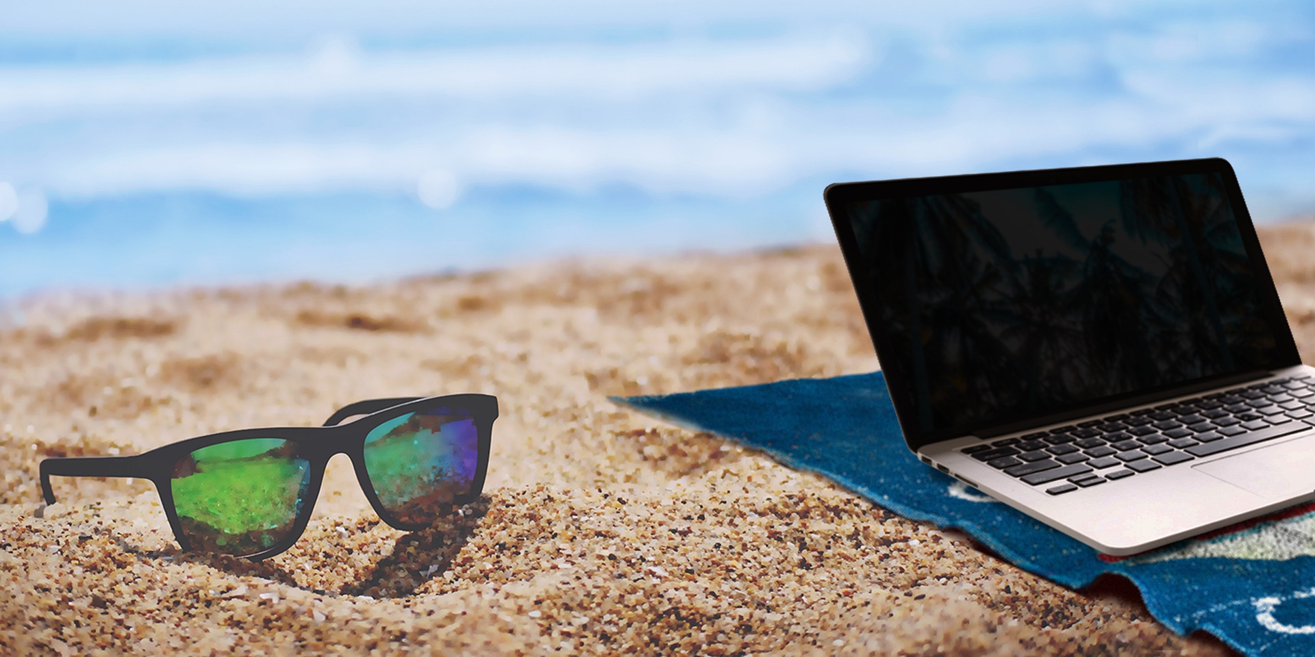 sunglasses and laptop with the ocean in the background